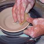 Hands making pottery.
